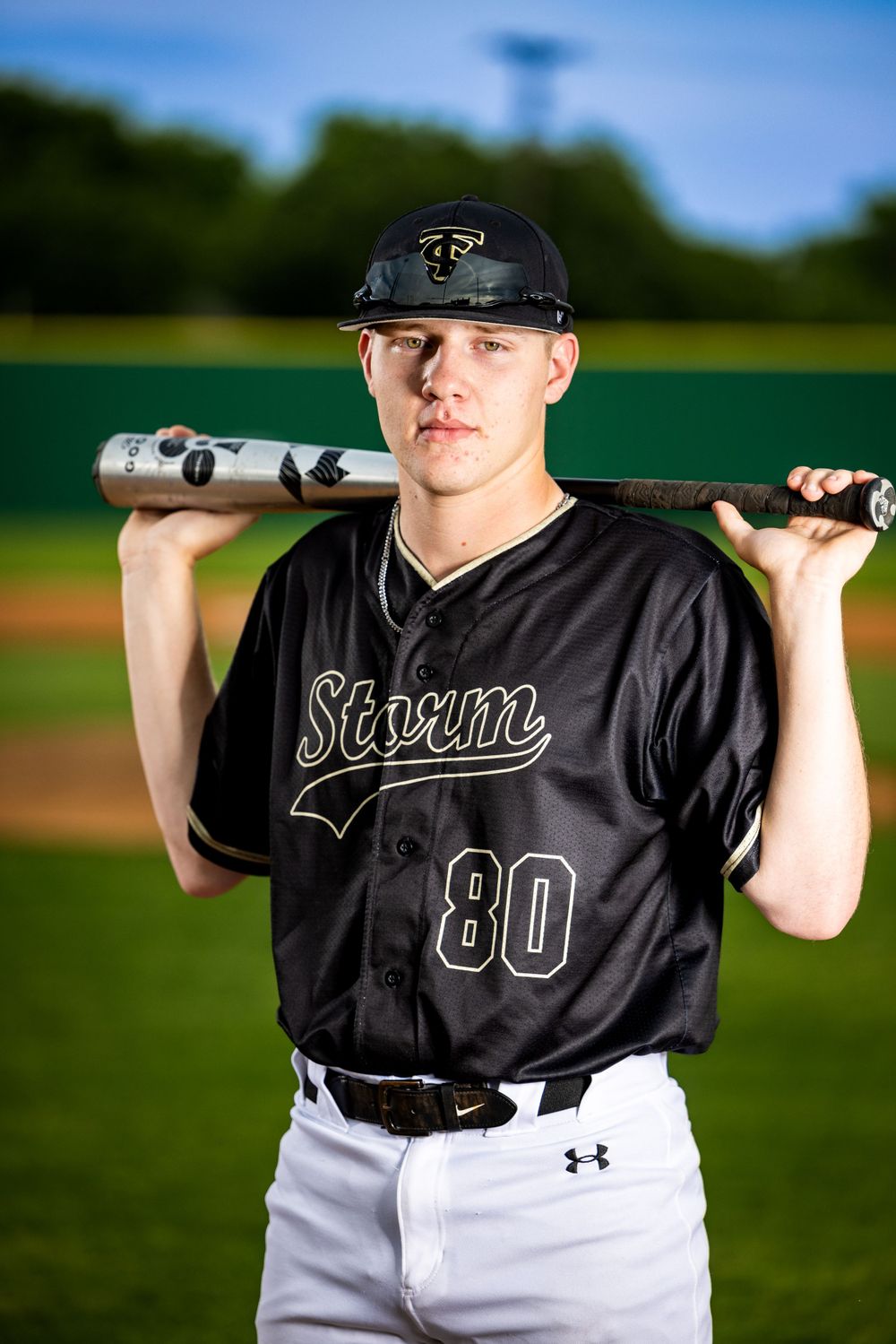Baseball player in black Storm jersey number 80 poses with bat on baseball field.