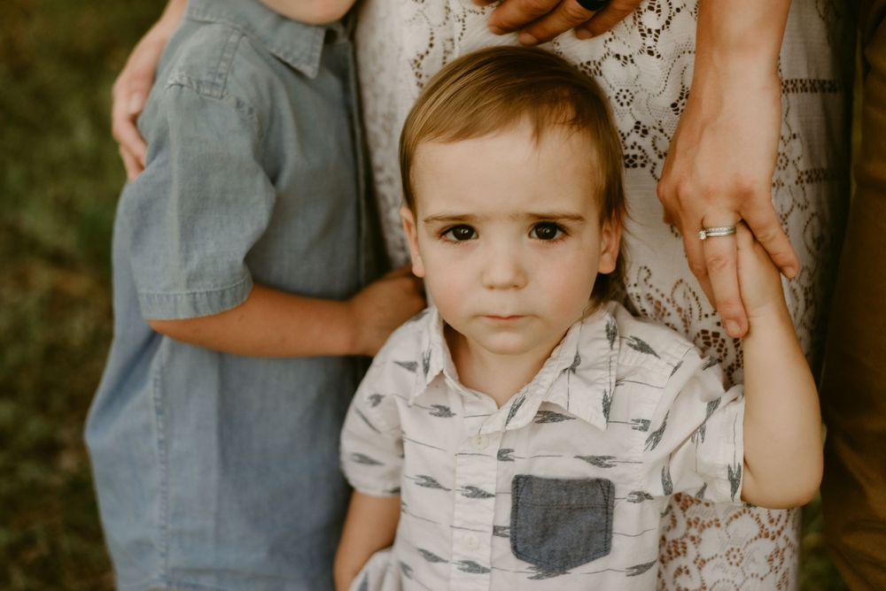 Close up portrait of young child in patterned shirt with pocket detail in outdoor setting.