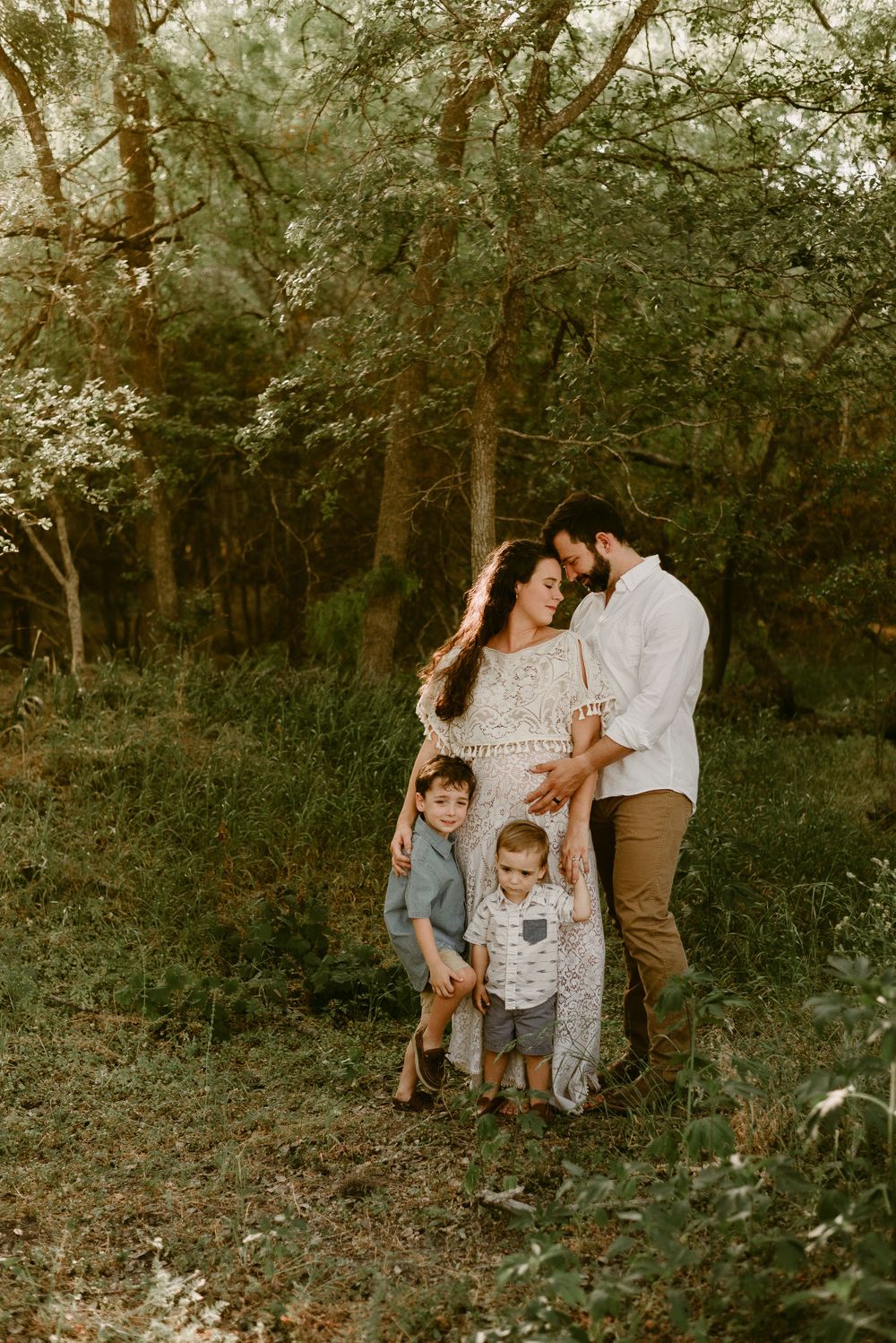 Family portrait in rustic woodland setting with warm evening light.