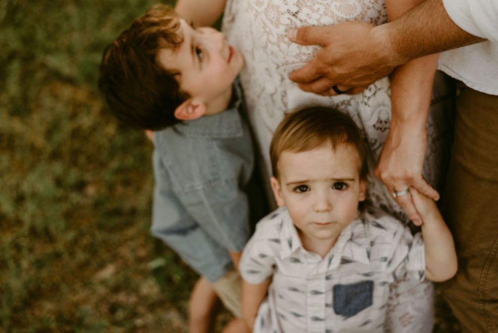 Two young children look up at their parents in a candid forest portrait.