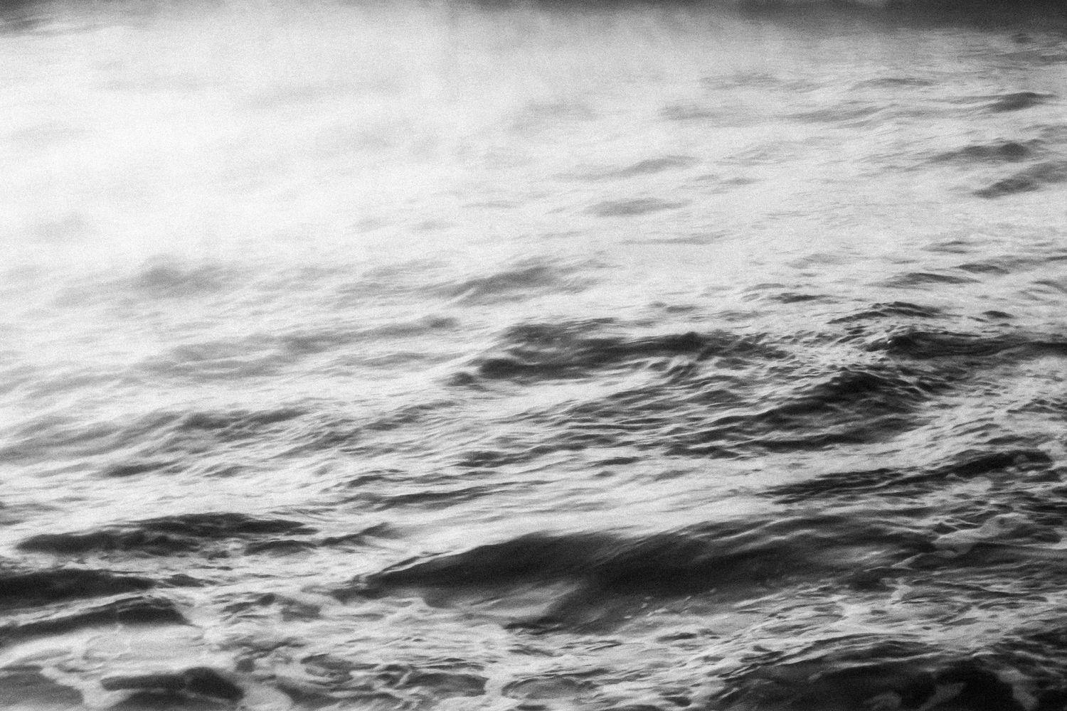 Black and white photograph of choppy ocean waves with dramatic lighting and texture.