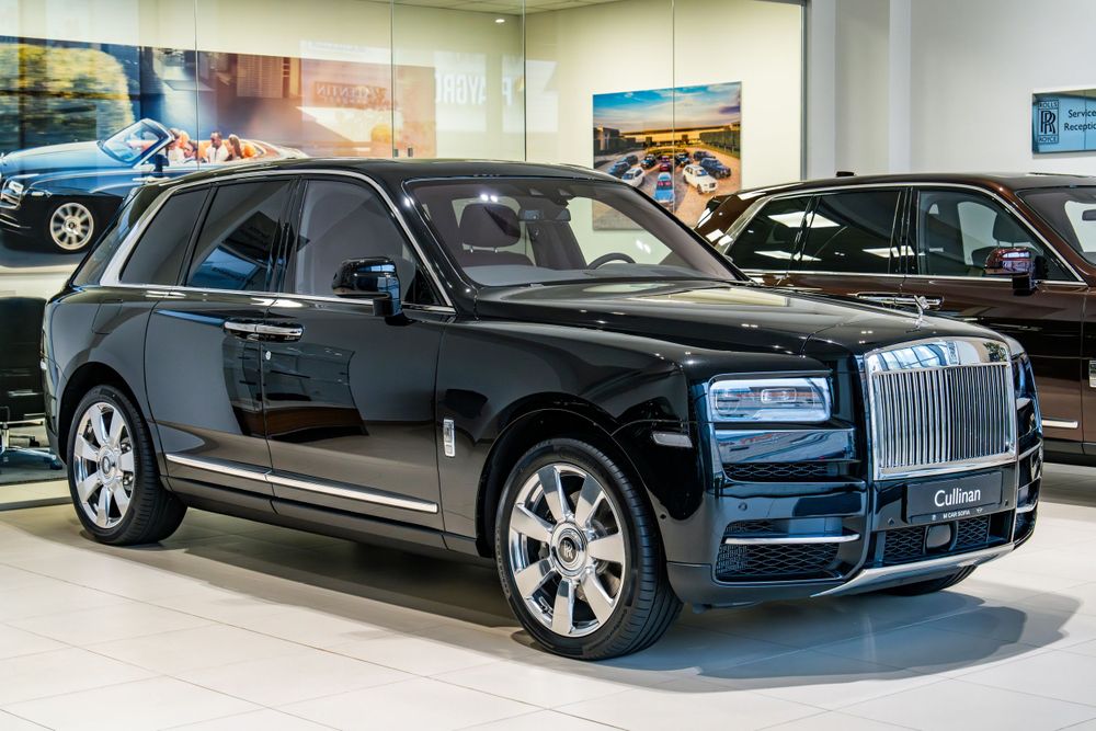 Black Rolls-Royce Cullinan SUV displayed in a luxury car showroom.