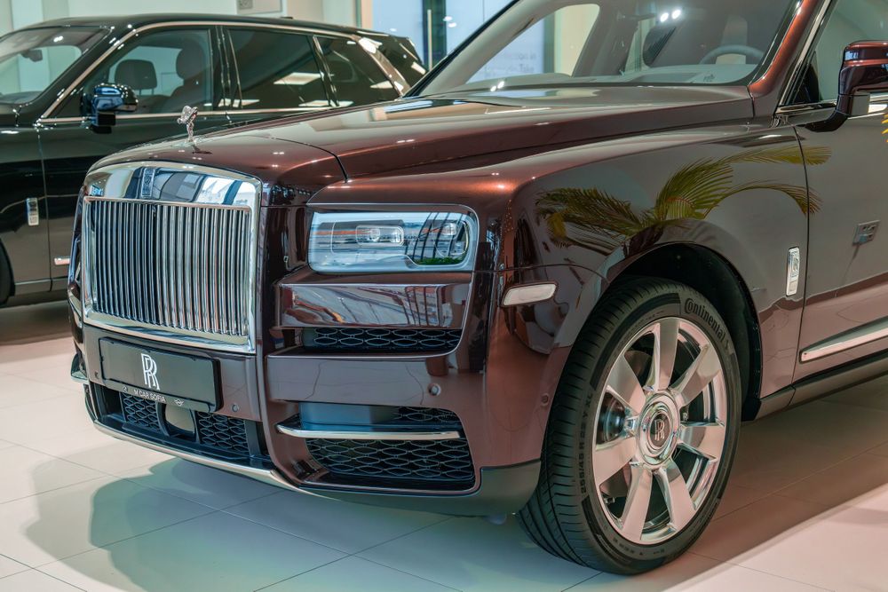 Front view of a burgundy Rolls-Royce Cullinan SUV showing the iconic grille and headlights.