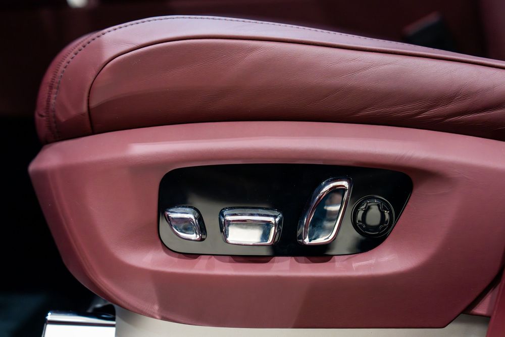 Power seat adjustment controls in red leather trim of a luxury vehicle.