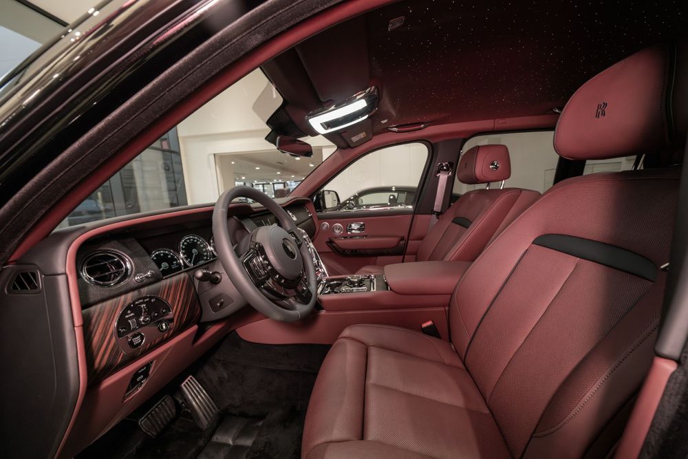 Luxurious red leather interior of a Rolls-Royce Cullinan showing front seats and dashboard.