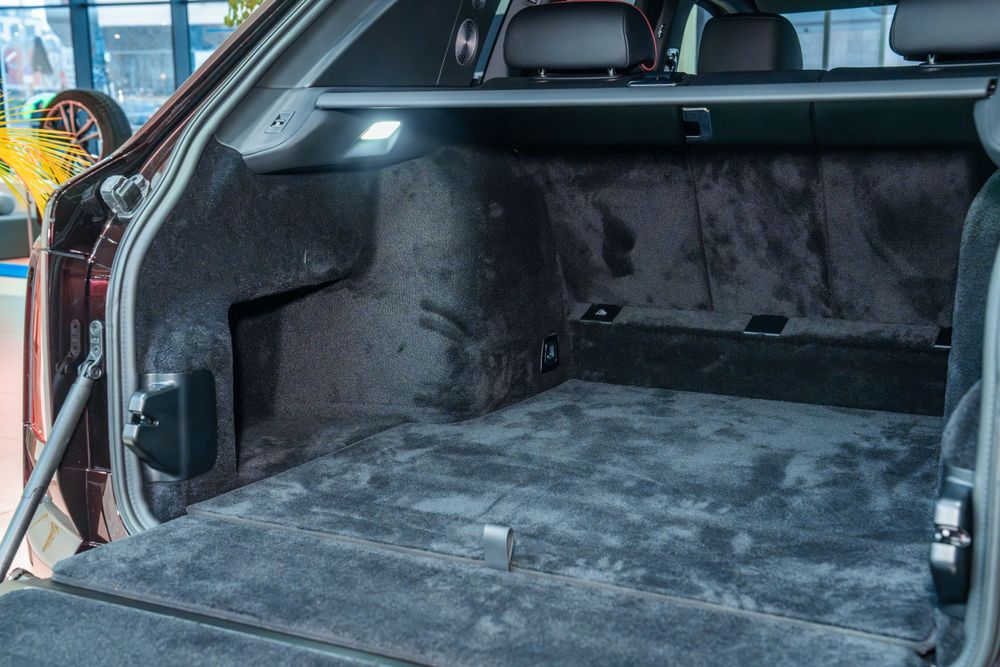 Interior view of a luxury vehicle's carpeted cargo area with dark grey upholstery.