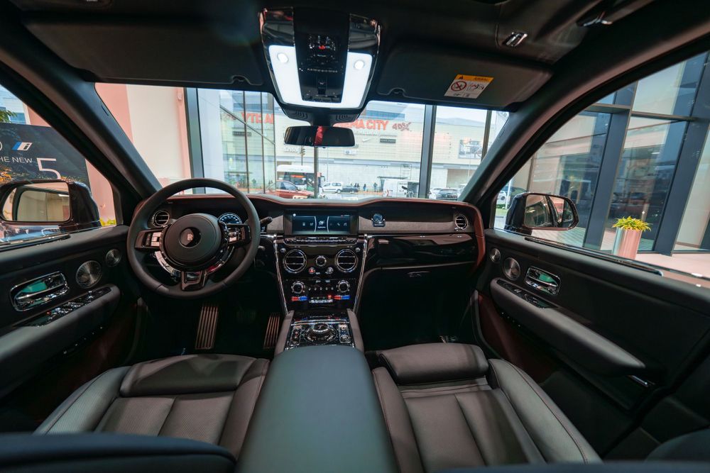 Interior dashboard and center console of a Rolls-Royce Cullinan featuring premium black leather.
