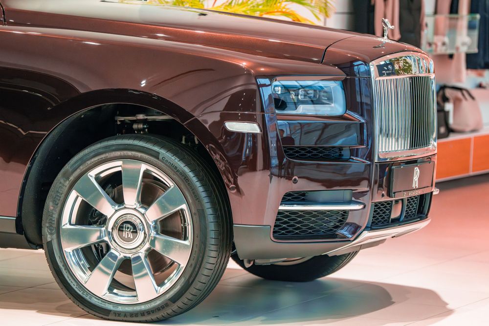 Detail shot of a burgundy Rolls-Royce Cullinan's front quarter panel and signature grille.