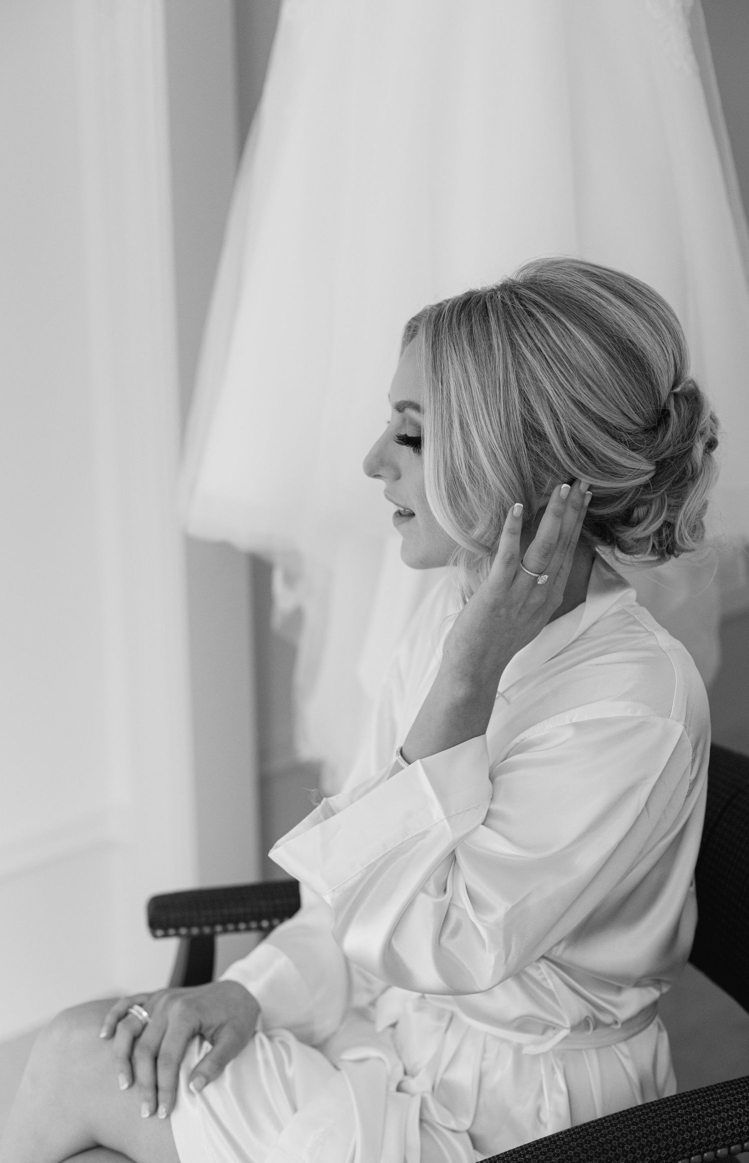Black and white portrait showing elegant bridal preparation moment.