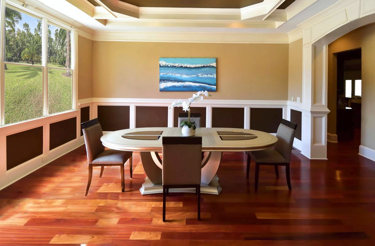 Modern dining room with hardwood floors, cream walls and tray ceiling featuring round tables and upholstered chairs.