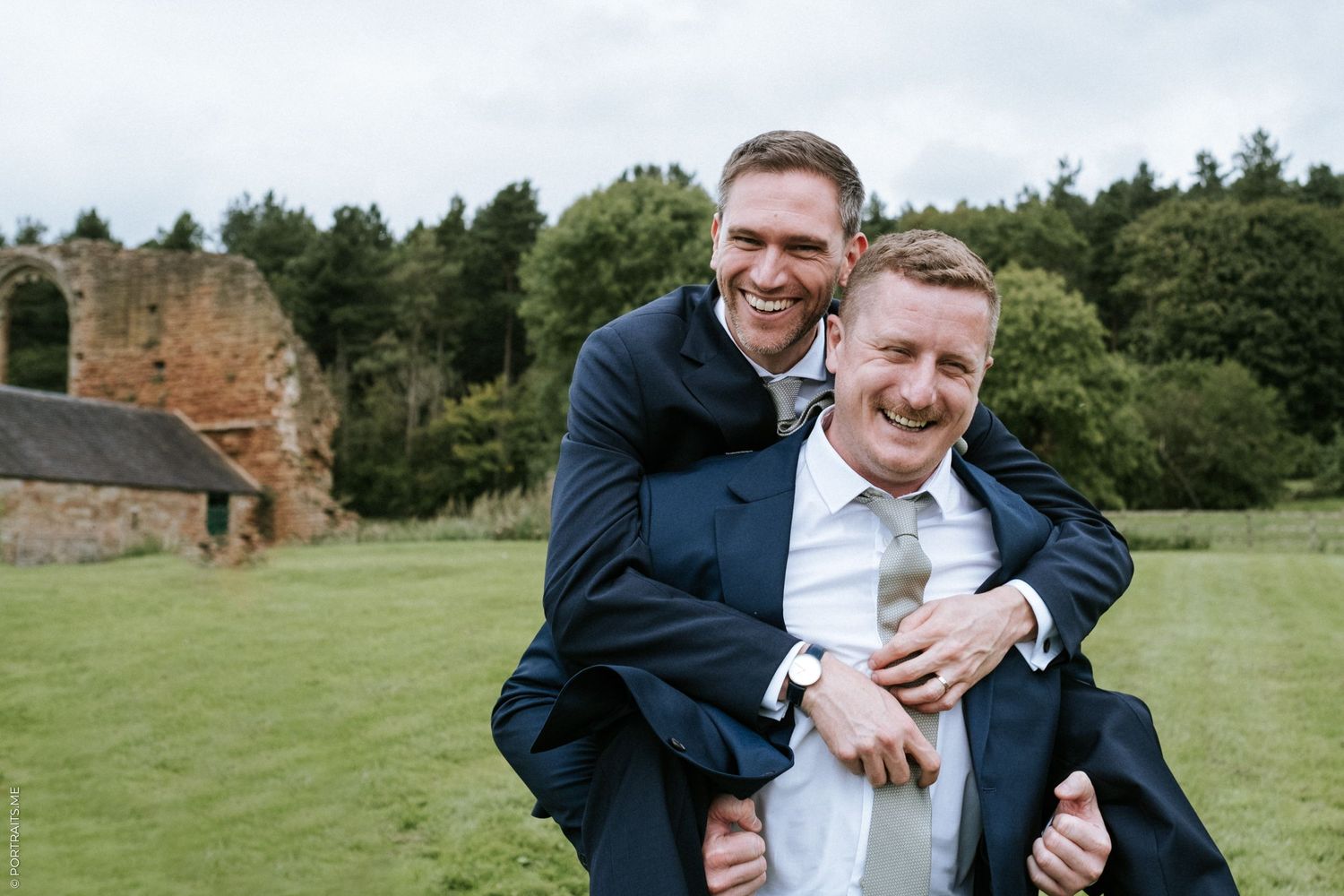 A best man jumps on the grooms back, at a country wedding.