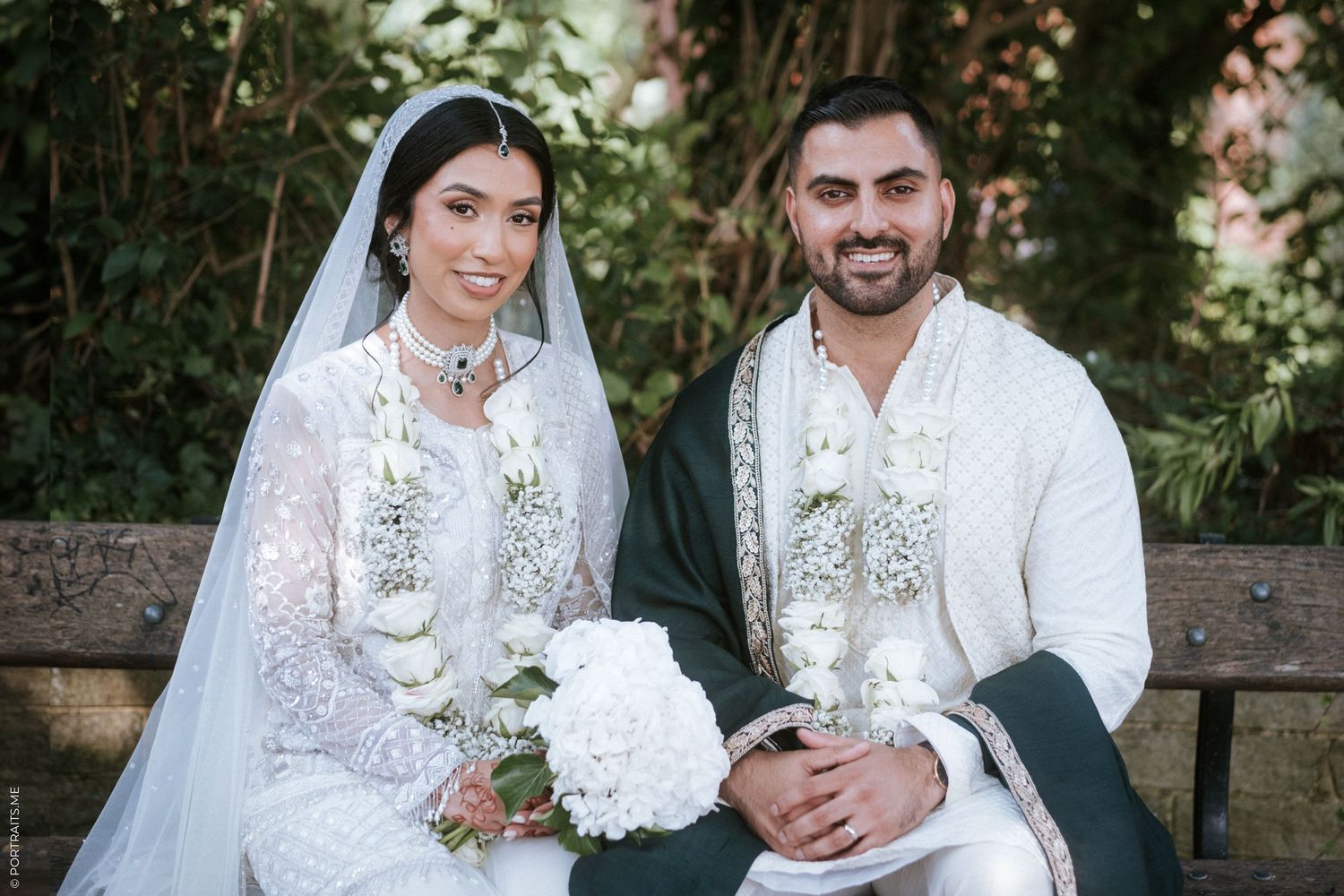 A muslim couple in traditional wedding attire sit under a tree in London.