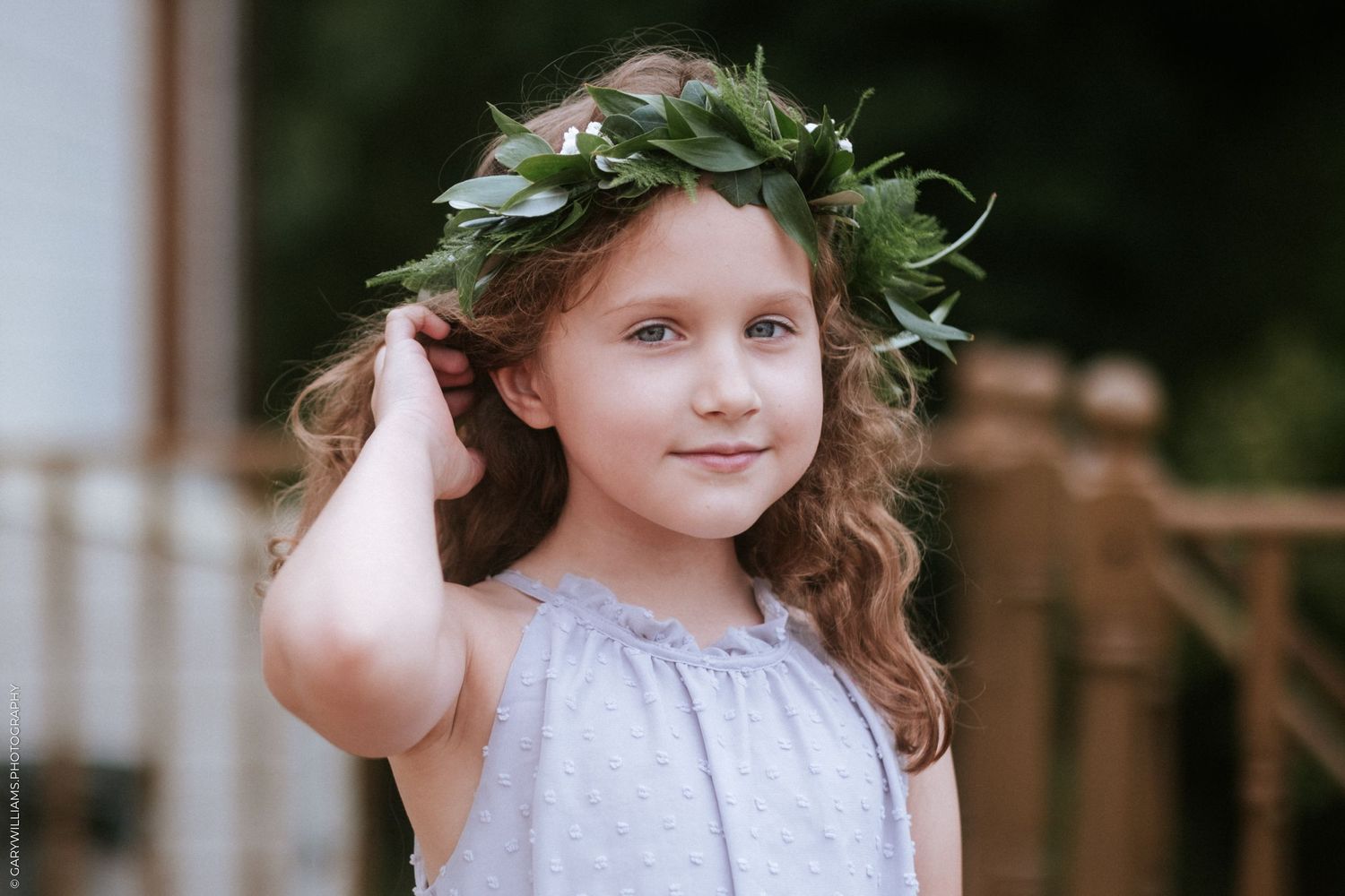 A flower girl with a floral crown adjusts her hair.