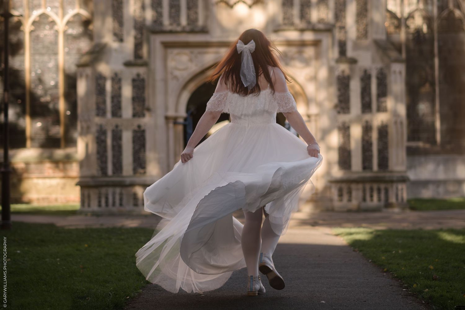 The back of a bride walking towards a grand building.