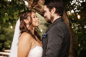 Romantic moment between newlyweds under trees with soft natural lighting.