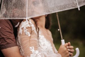 Close-up detail of delicate lace wedding dress and umbrella handle.