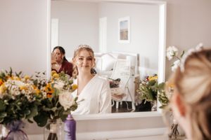 Bridal preparations with floral arrangements reflected in a bright vanity mirror. Photo at Fiddling Fisherman Lookout Souris PEI