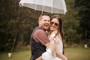 A couple shares a joyful moment under a clear umbrella during their wedding celebration.