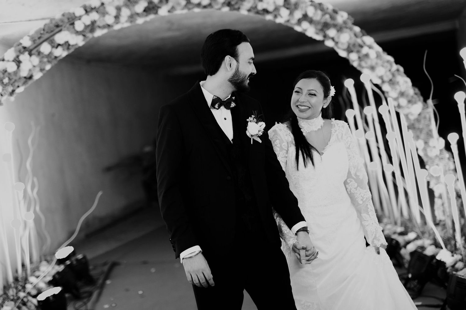 Wedding party gathering under elegant white floral arch decorations.