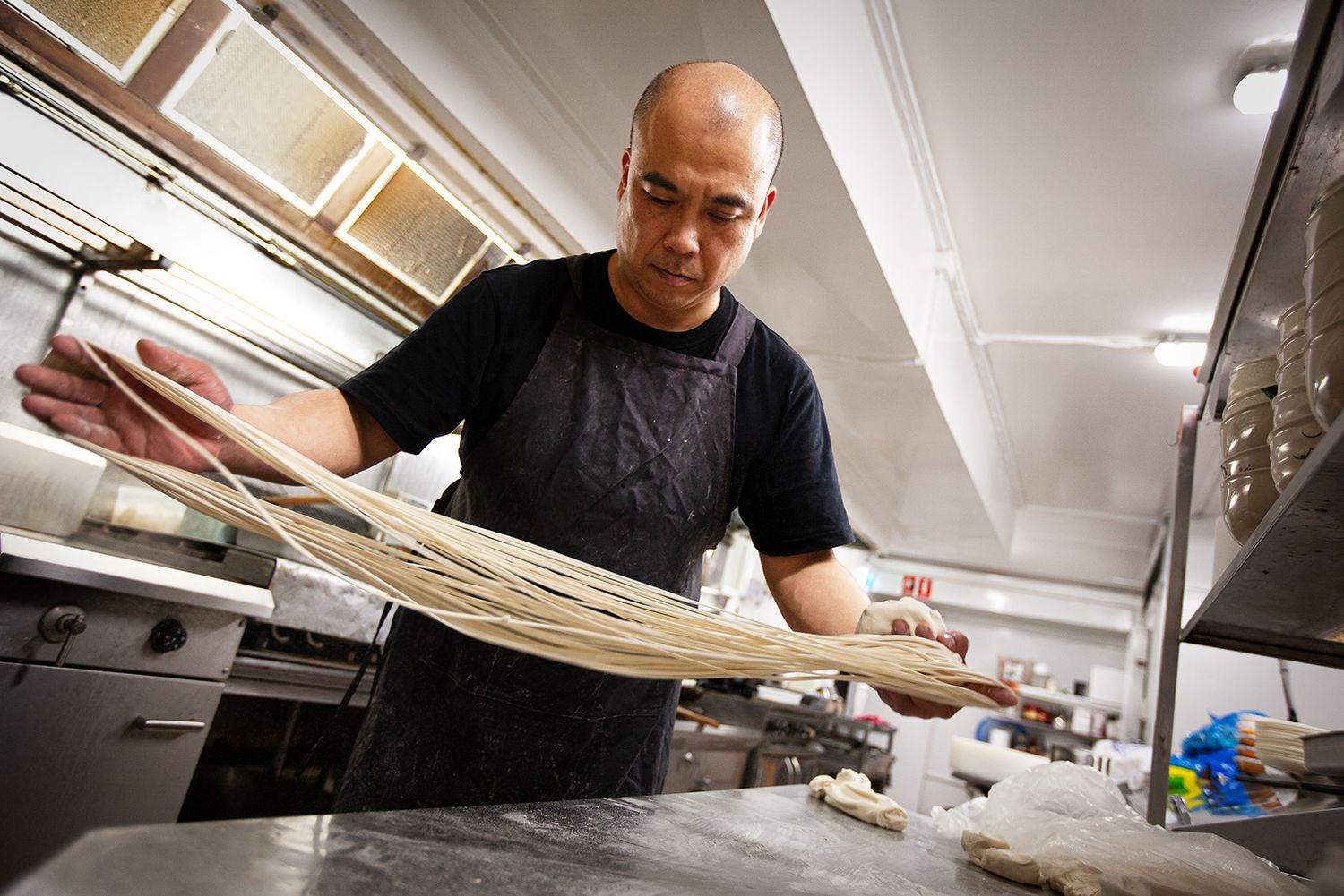 A Chinese hand-pulled noodle chef making noodles in his restaurant kitchen