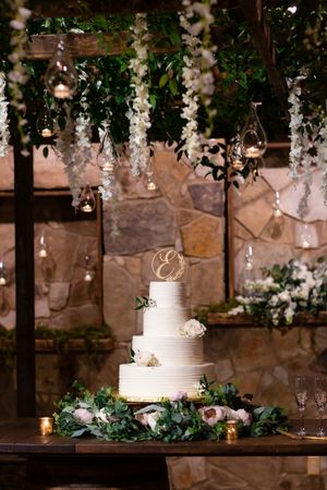 Wedding cake surrounded by hanging greenery and florals at wedding in Houston, TX.