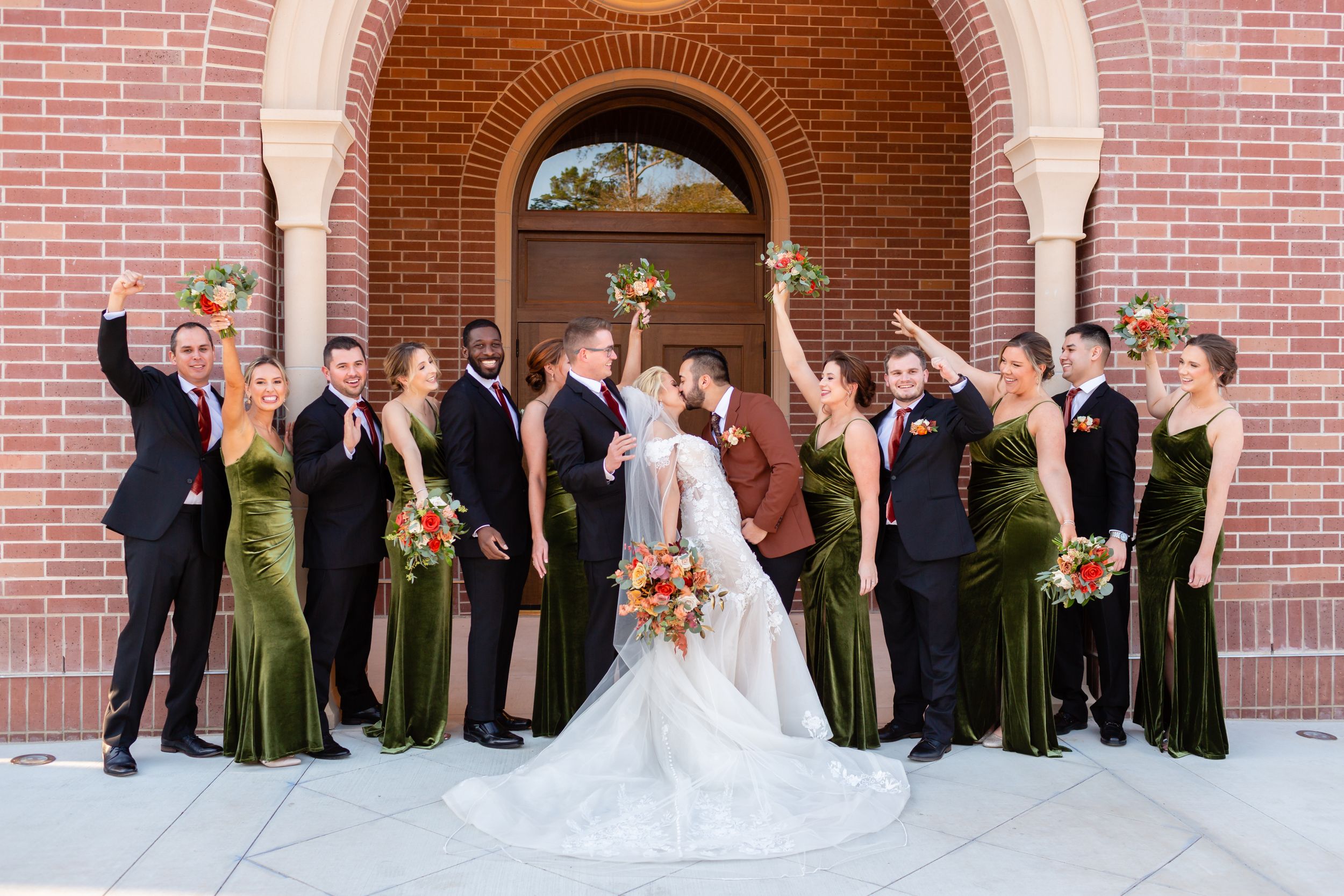 Wedding party cheers for the bride and groom while they kiss in Houston, TX.