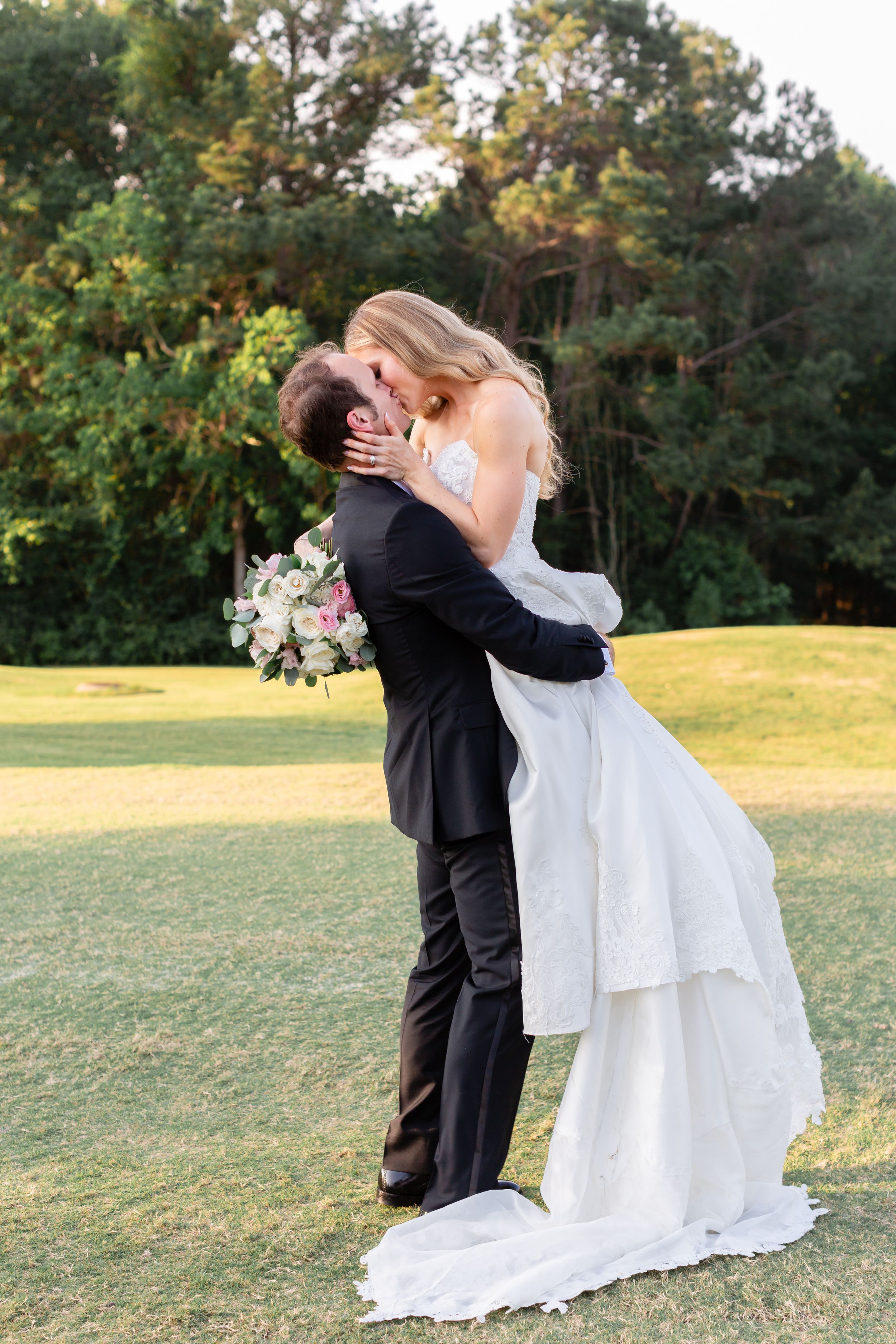 Groom lifts bride and kisses her after their wedding the Woodlands Country Club in The Woodlands, TX.
