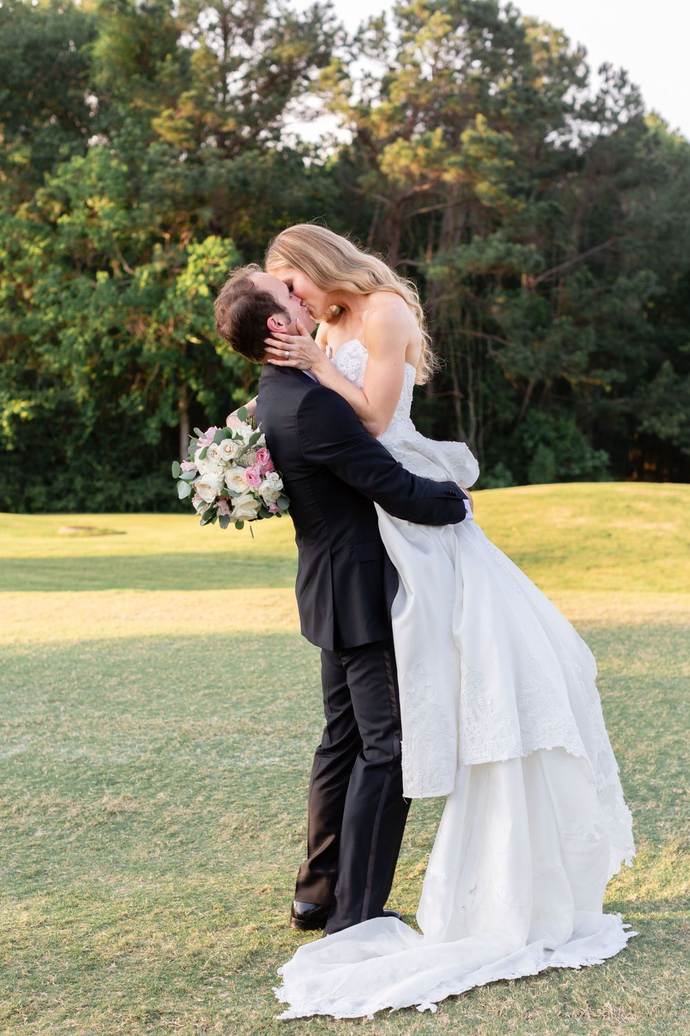 Groom lifts bride and kisses her after their wedding the Woodlands Country Club in The Woodlands, TX.