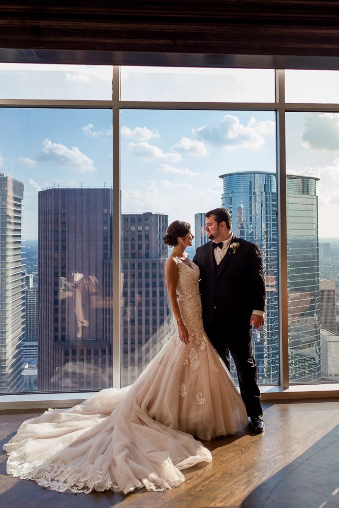 35 floors up, a bride and groom look towards one another with city views behind them at the Petroleum Club in Houston, TX.