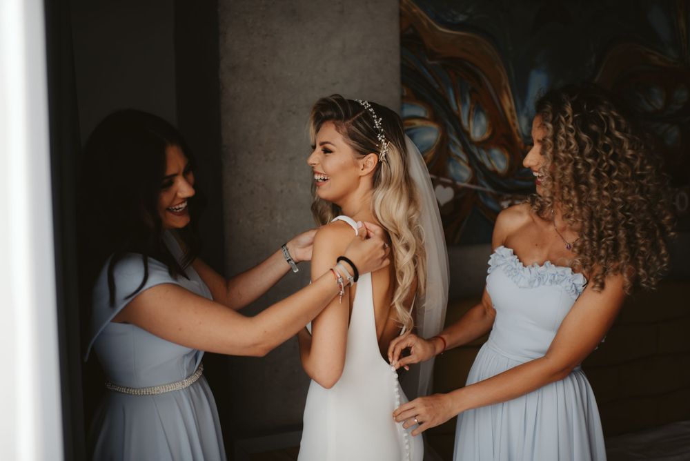 Bridesmaids in powder blue dresses assist with final wedding day preparations.