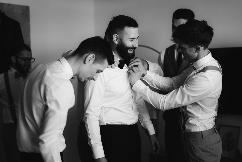 Black and white photo of groomsmen laughing together during wedding preparations.