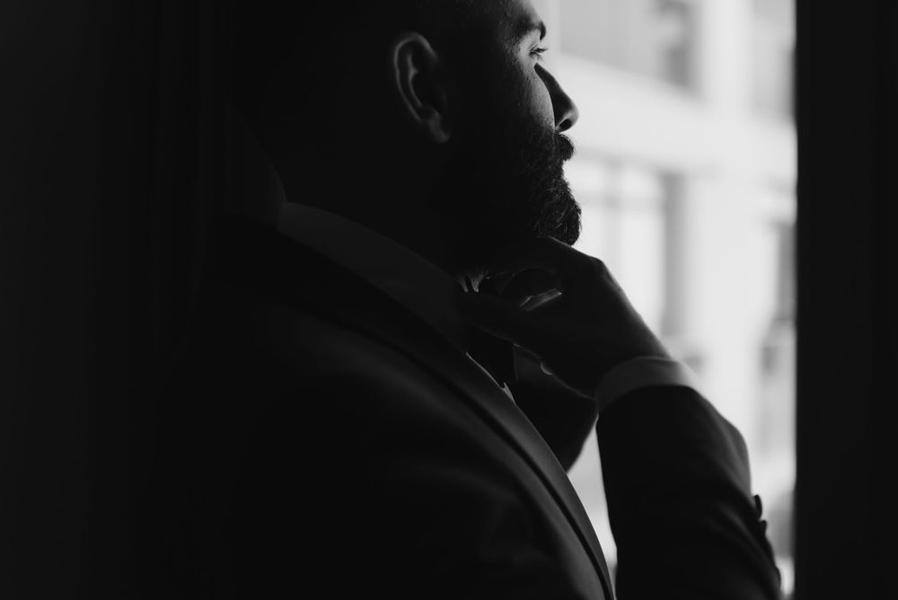 Silhouette profile of a figure looking up by a window in dramatic black and white lighting.