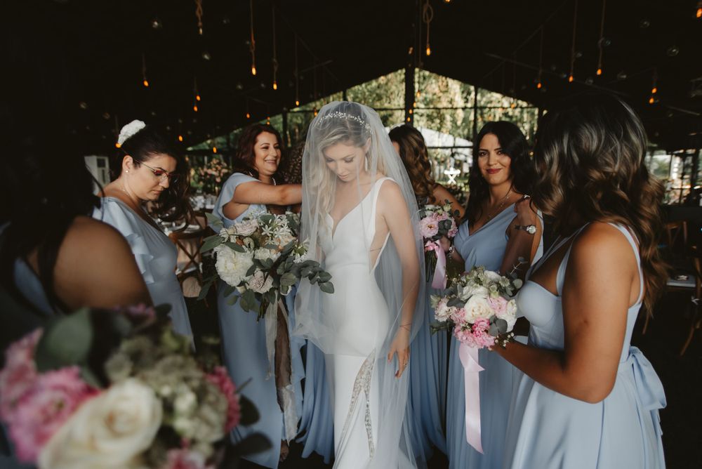 Wedding party gathered together holding bouquets in a beautifully decorated indoor venue.
