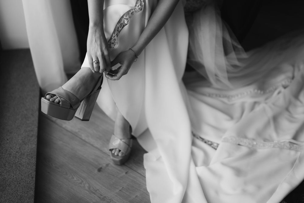 Close-up detail shot of a bride's feet as she puts on sparkly wedding heels.