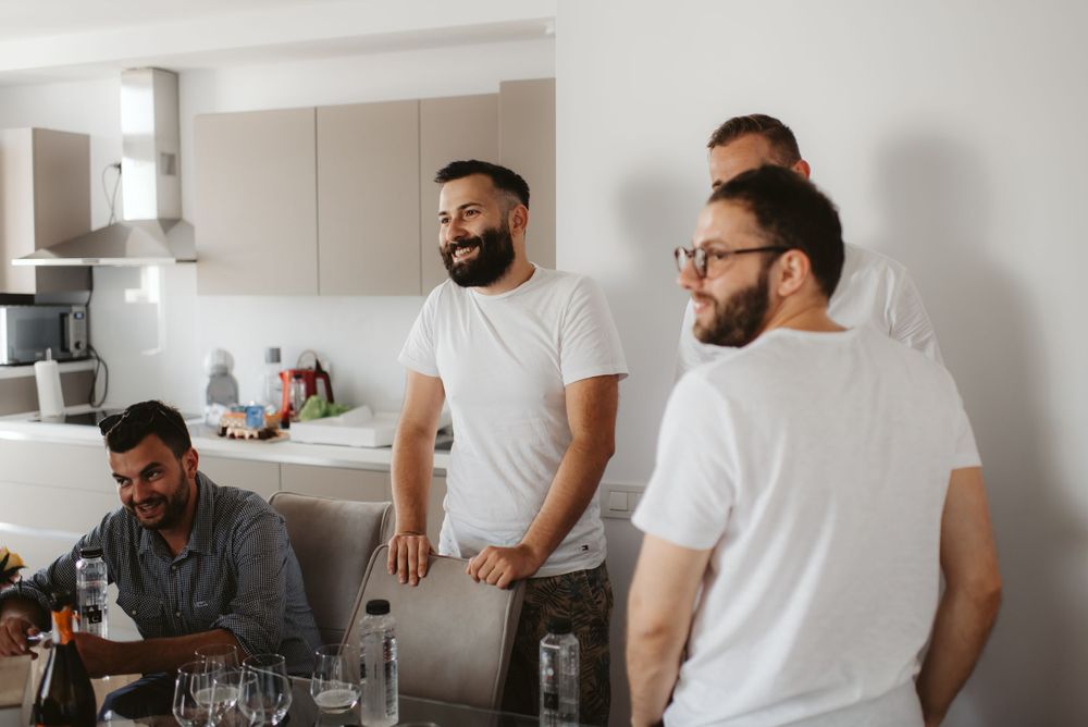 Wedding party members gathered in a modern kitchen wearing white shirts.