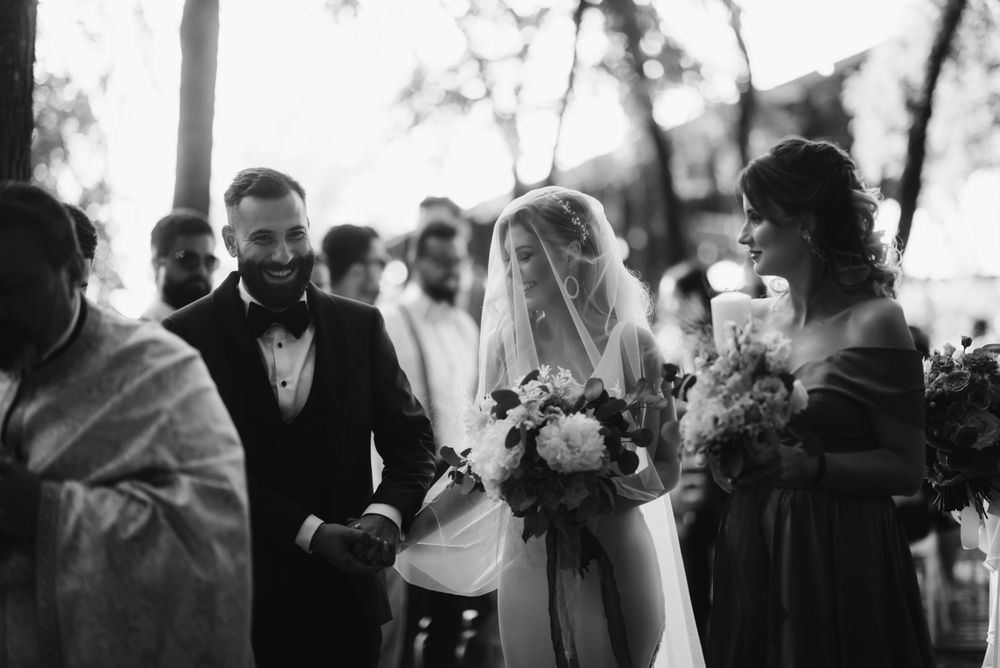 Black and white candid photo of wedding ceremony in progress with guests watching.
