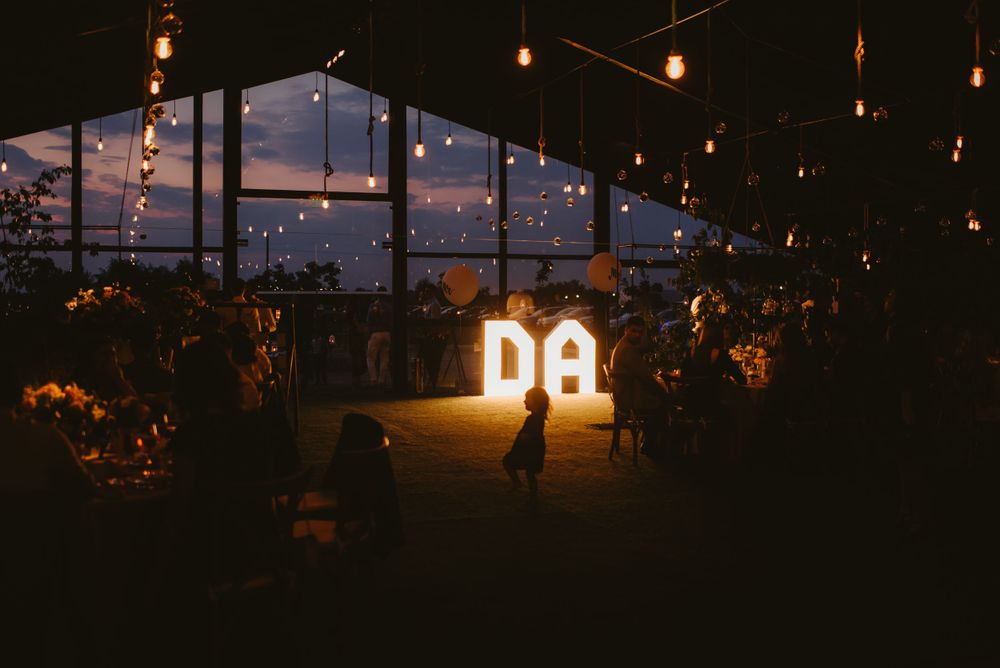 Glowing venue interior with string lights and illuminated letters at night.