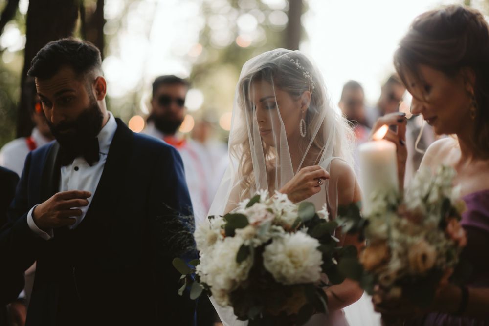 Intimate outdoor wedding ceremony moment with floral bouquets in natural lighting.
