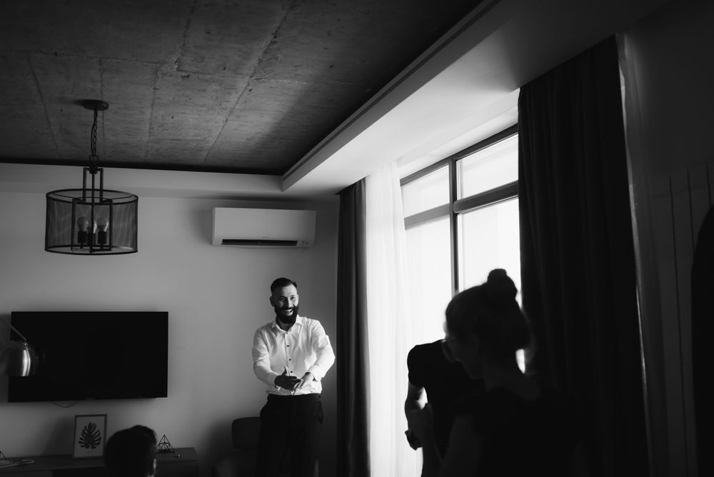 Silhouetted figure standing in a modern room with large windows and pendant lighting.