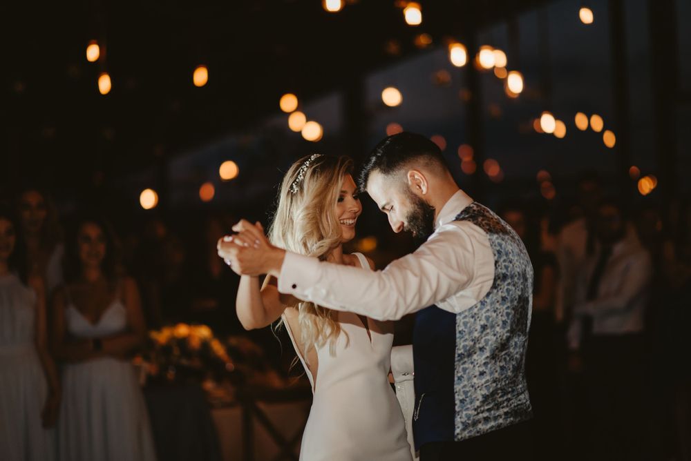 Couple shares a romantic dance moment under ambient reception lighting.