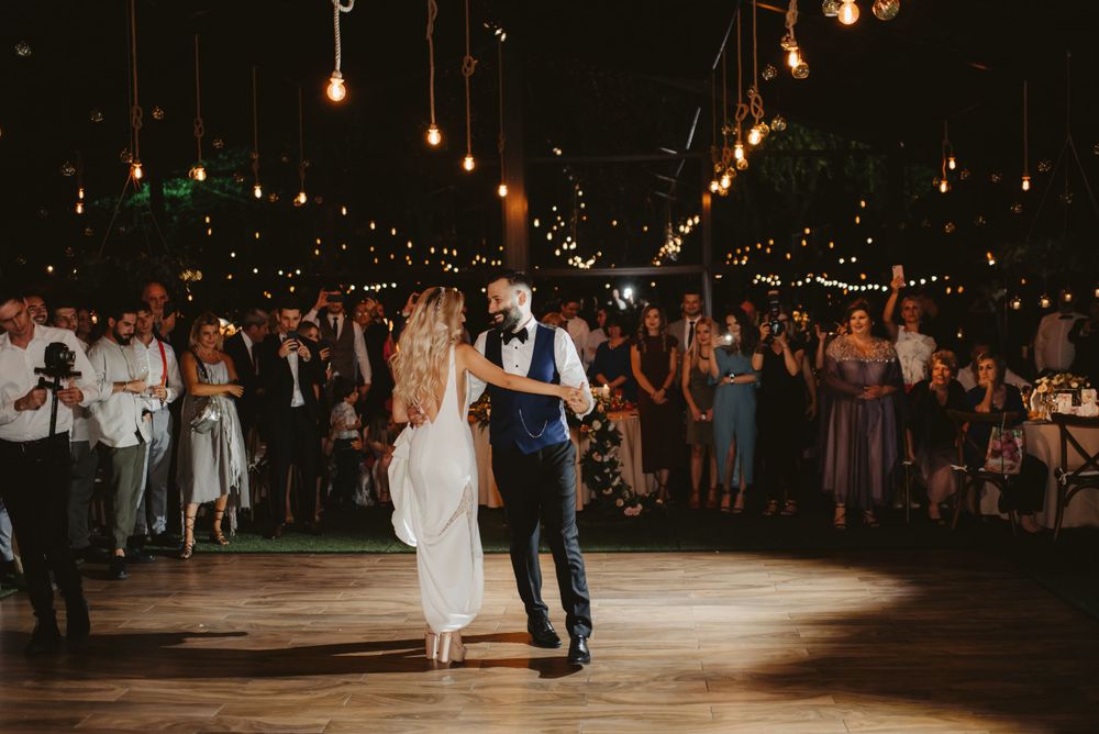 Couple performs their first dance on spotlit floor while guests watch from the sides.