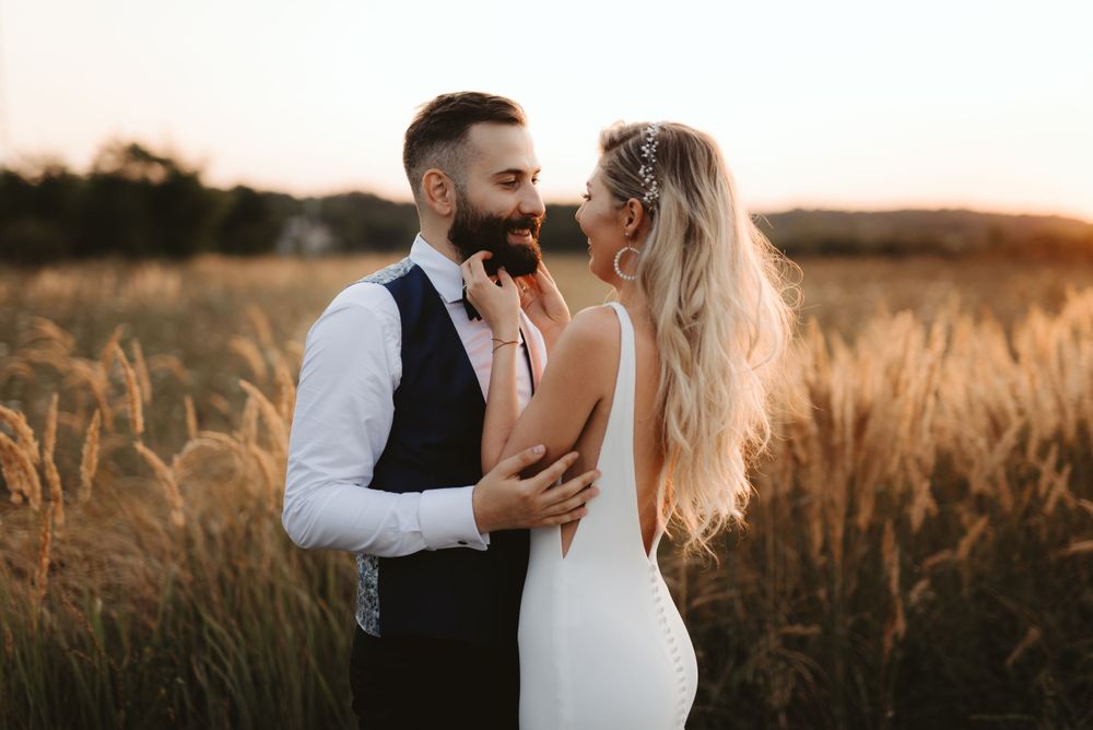 Couple shares intimate moment in golden wheat field during sunset wedding photoshoot.