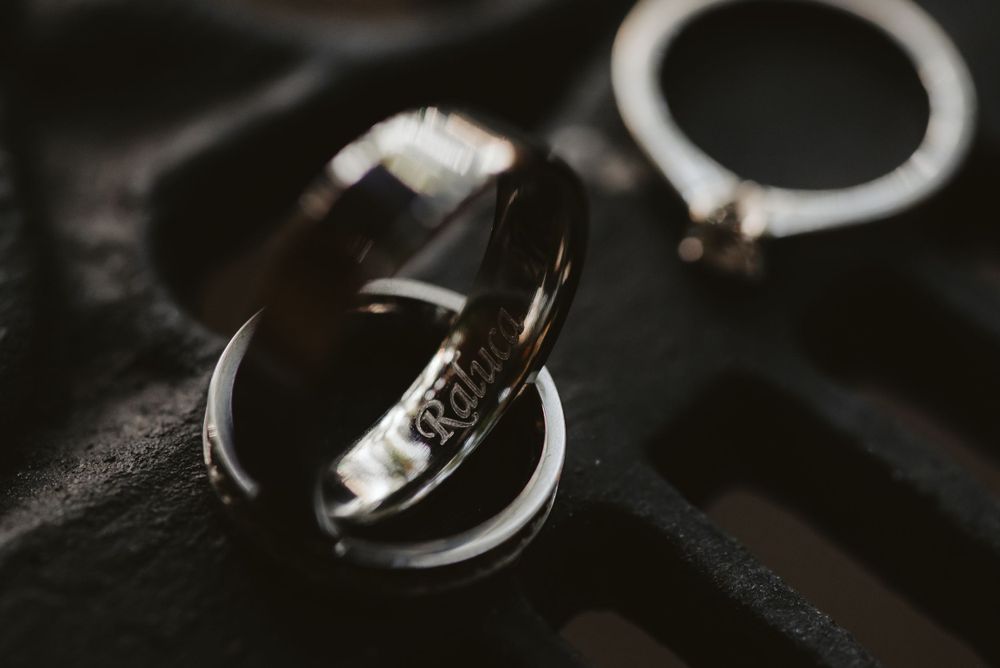 Artistic close-up of wedding rings with dramatic lighting on dark background.