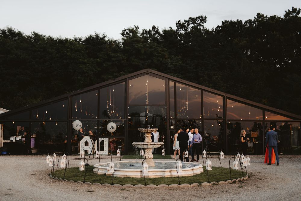 Modern wedding venue with illuminated fountain and string lights at dusk.