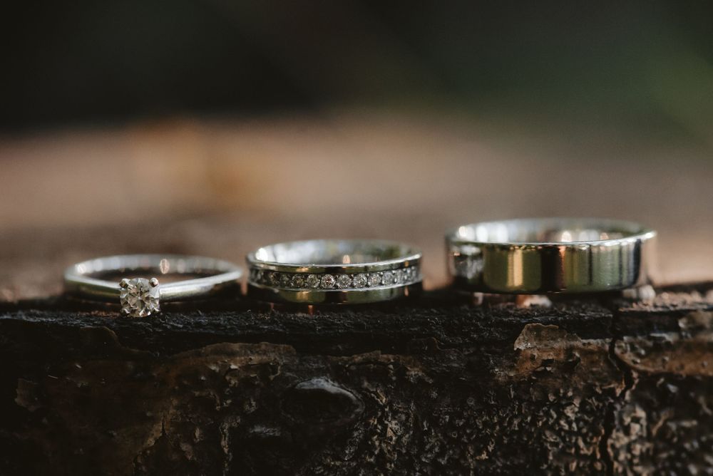 Collection of wedding rings and bands arranged on rustic wooden surface.