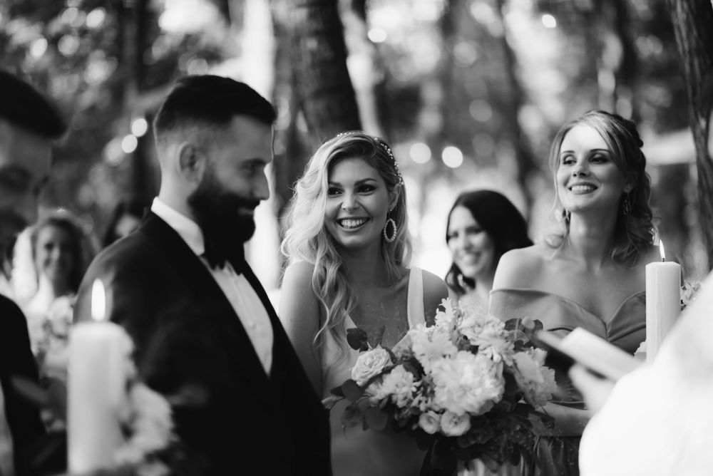 Black and white candid moment during outdoor forest wedding ceremony.
