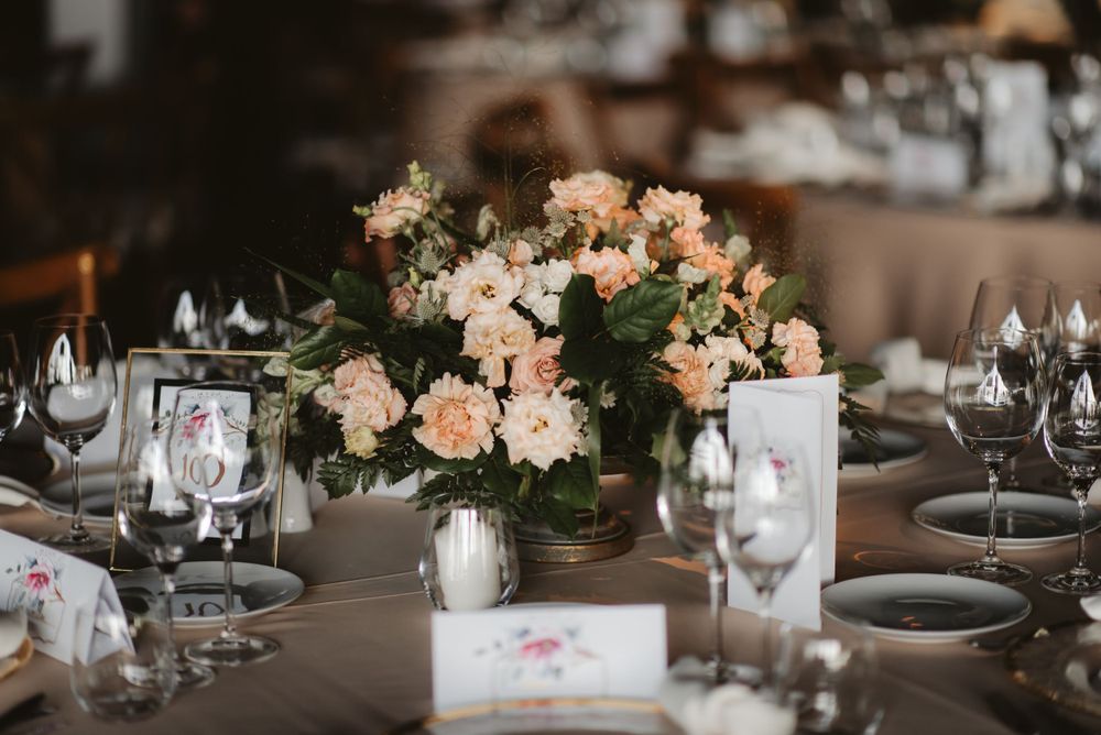 Wedding reception table with peach floral centerpiece and formal place settings.