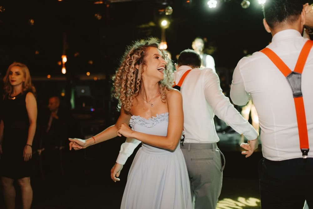 A guest in a light blue dress dances joyfully at a celebration.