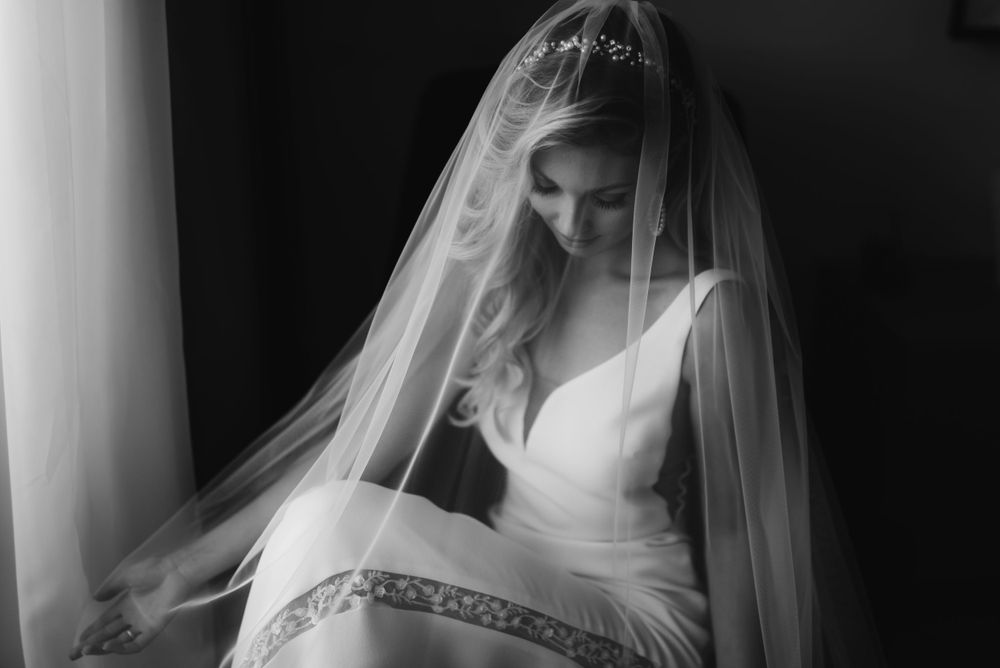 Dreamy black and white bridal portrait with a flowing veil and classic V-neck wedding dress.