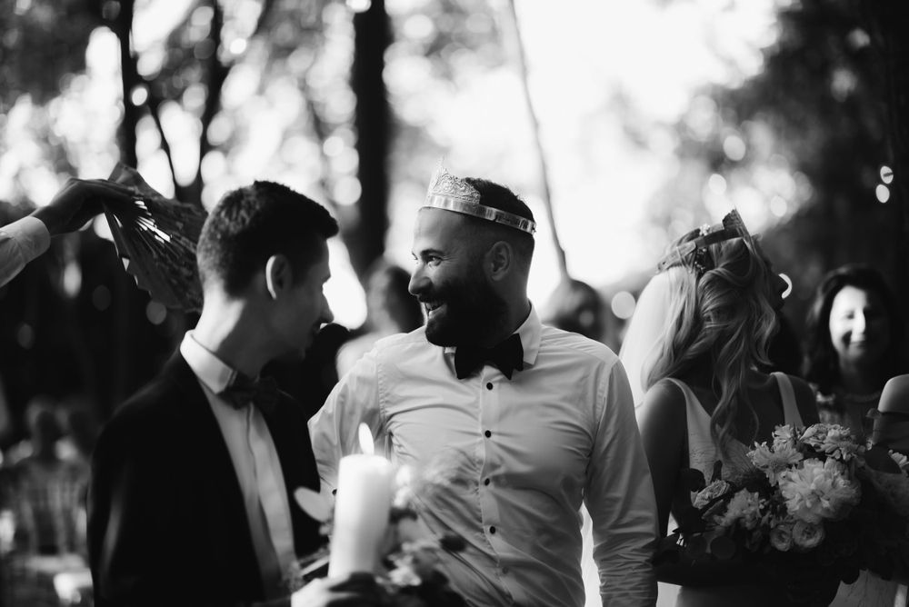 Black and white candid photo of guests conversing during outdoor wedding celebration.